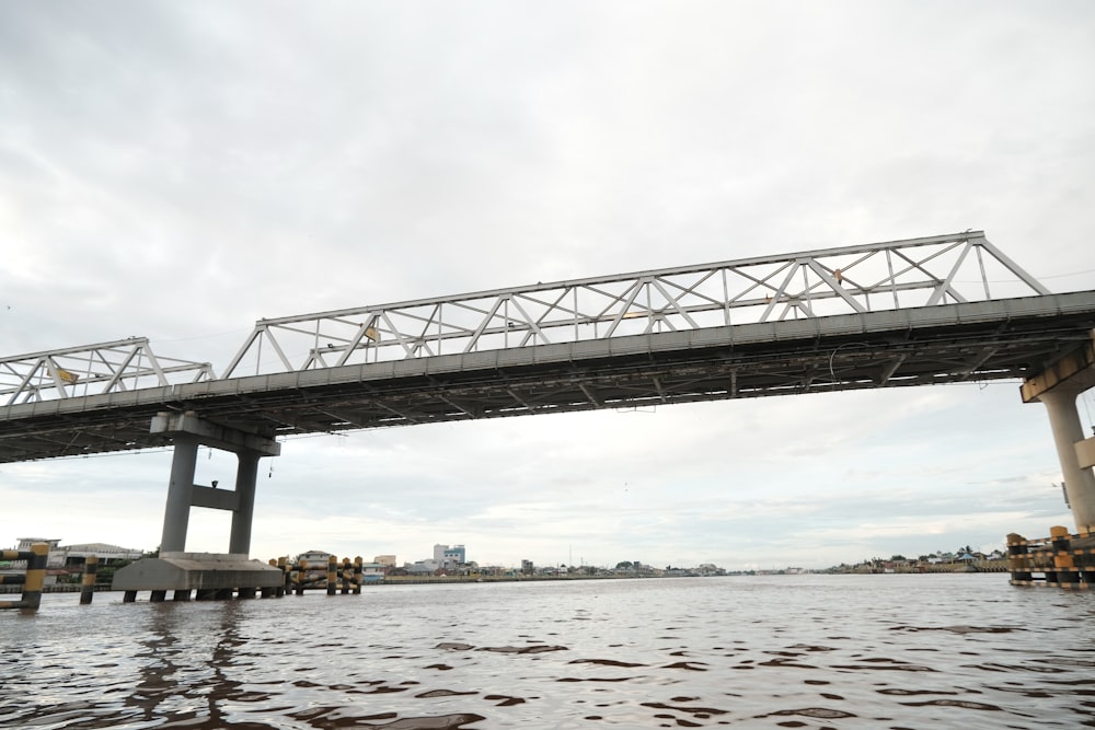 pont en acier gris au-dessus d’un plan d’eau pendant la journée