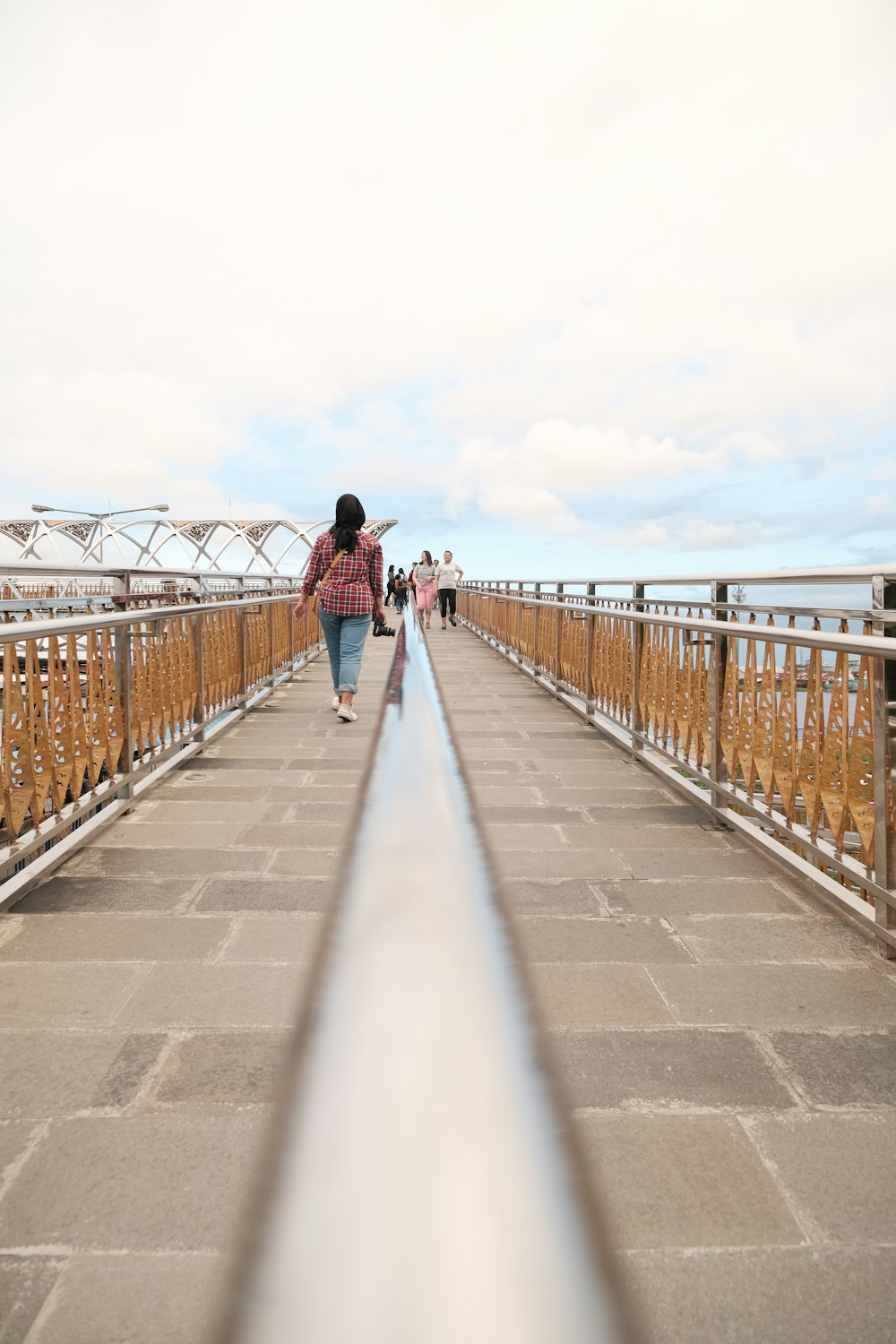 Donna in giacca nera che cammina sul ponte durante il giorno