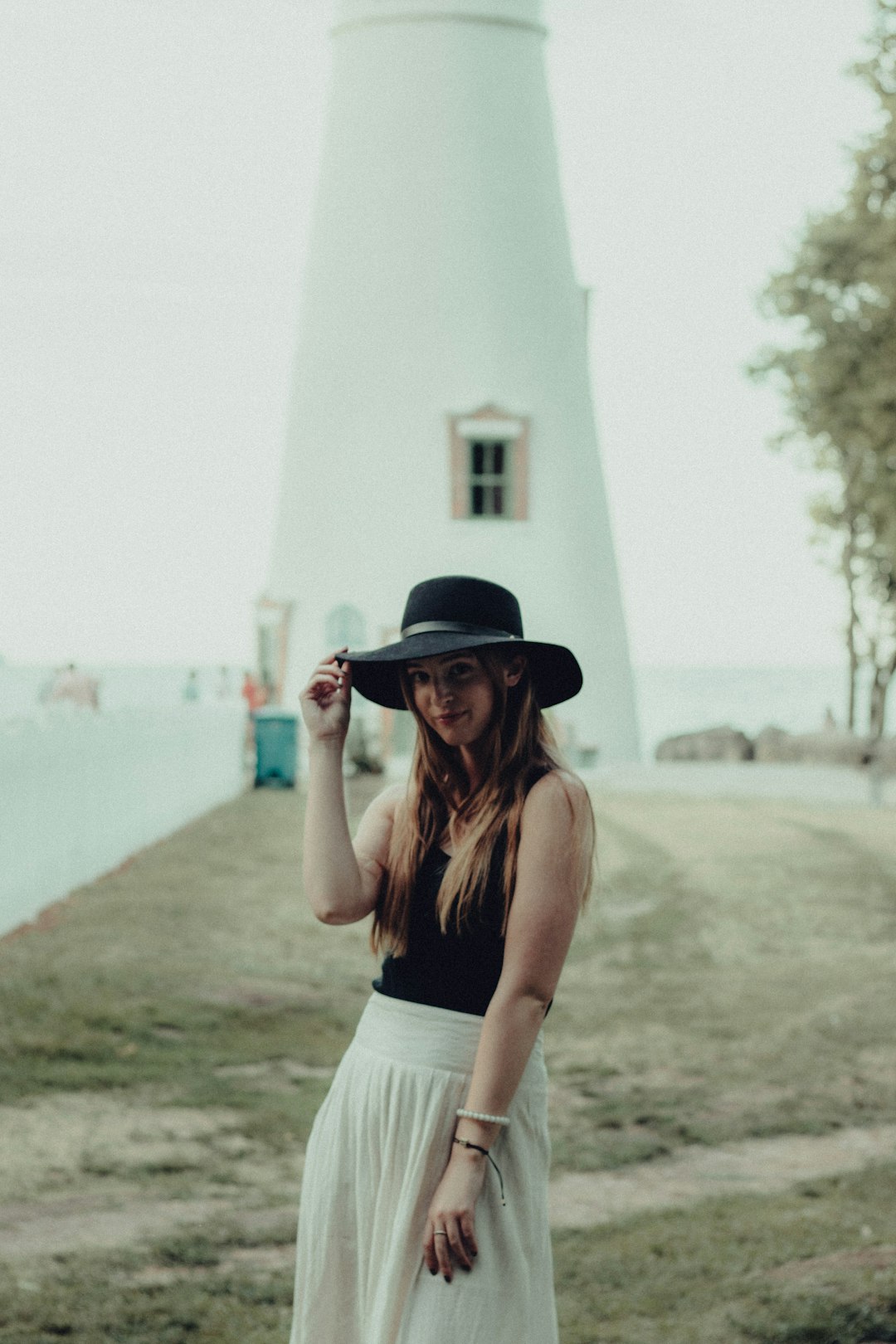 woman in white tank top and black and white striped skirt standing on brown field during