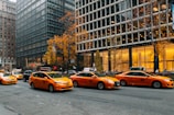yellow taxi cab on road near high rise buildings during daytime