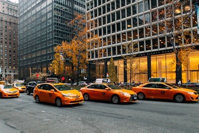 yellow taxi cab on road near high rise buildings during daytime