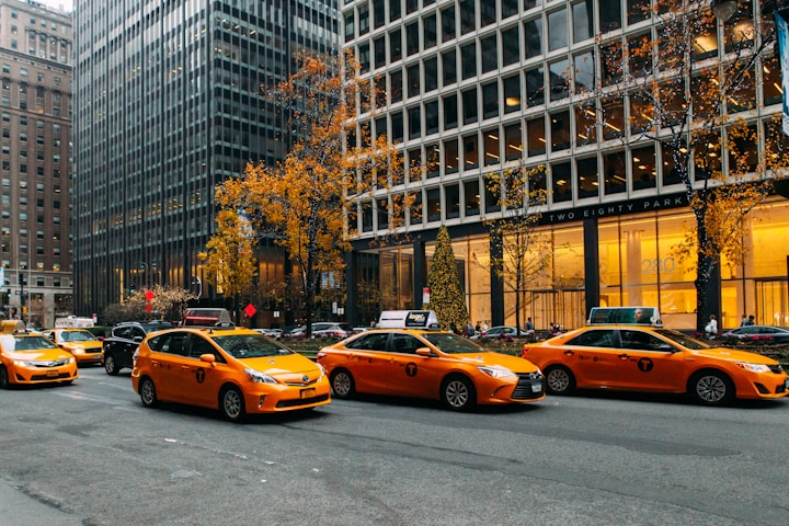 yellow taxi cab on road near high rise buildings during daytime