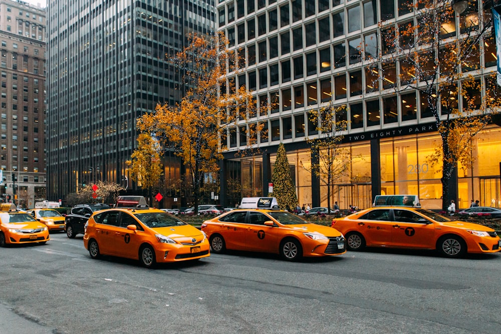 yellow taxi cab on road near high rise buildings during daytime