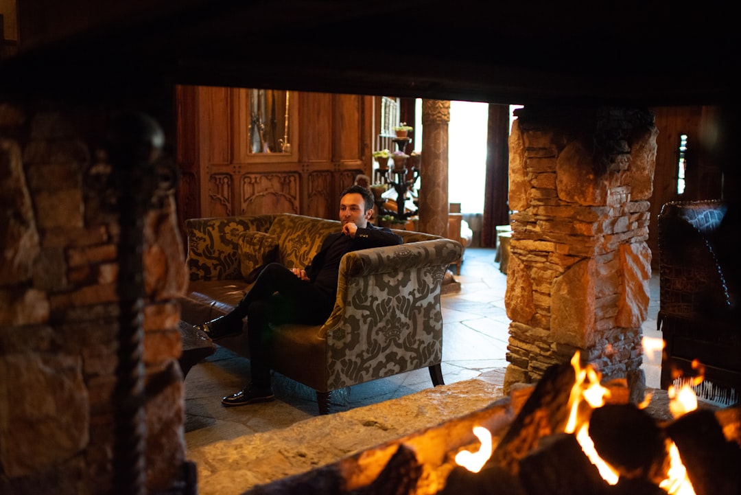 man in black jacket sitting on brown wooden armchair,