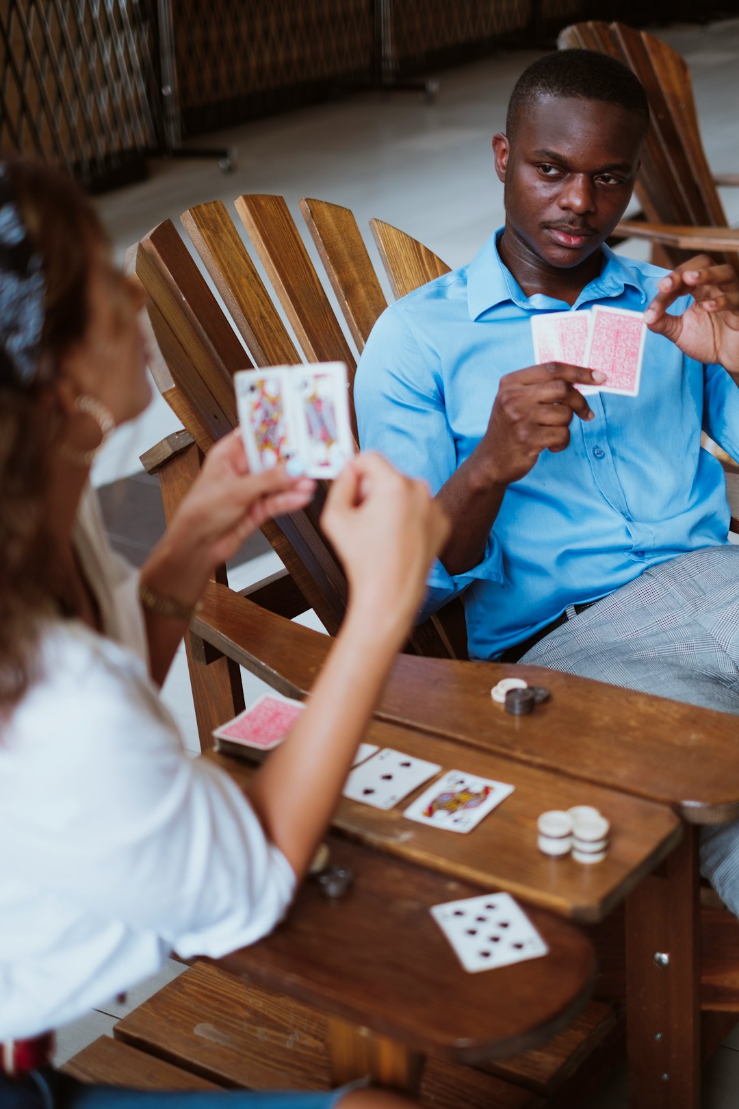 man in blue button up shirt holding playing cards