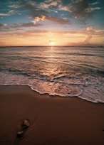 ocean waves crashing on shore during sunset