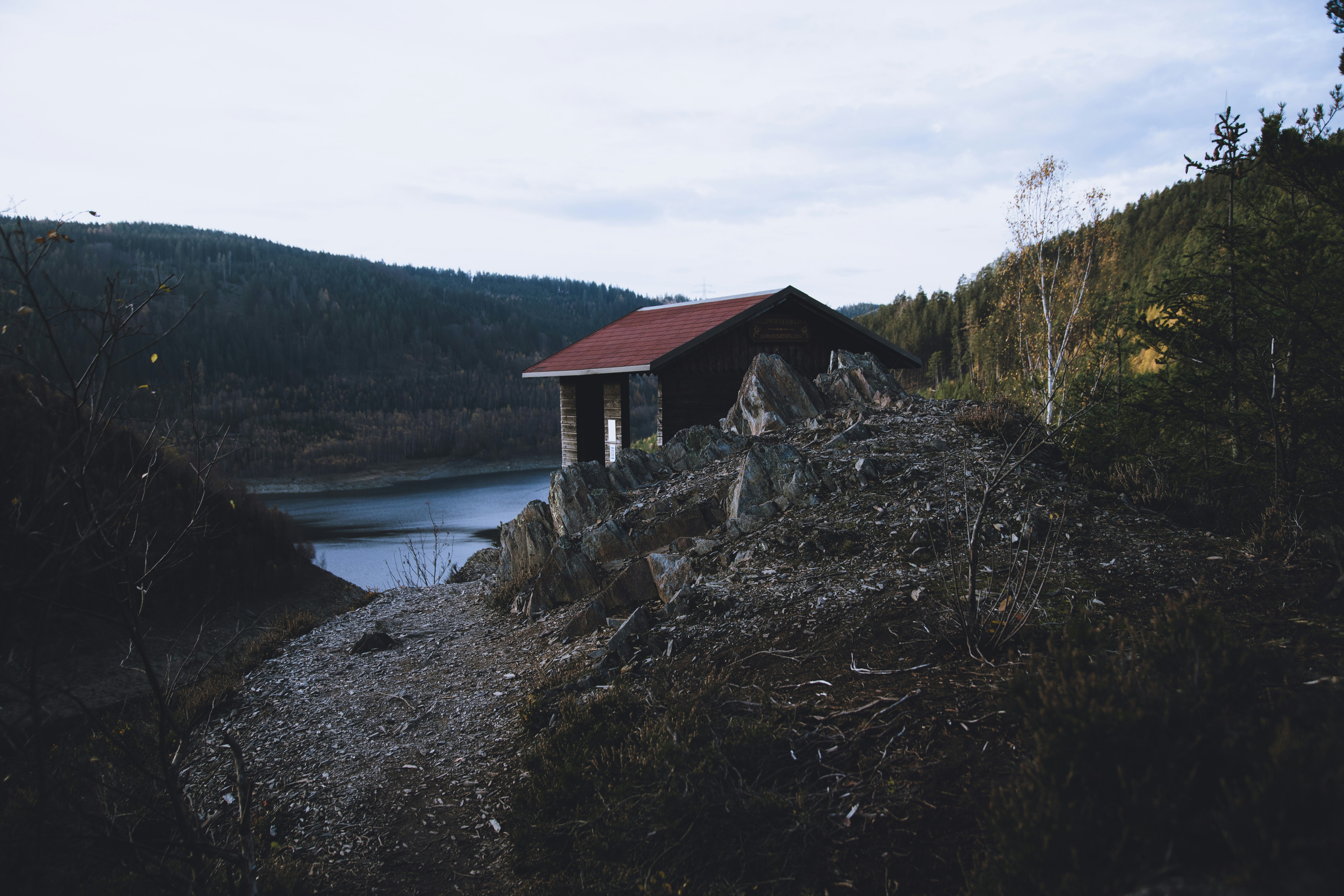 brown wooden house near lake under white clouds during daytime