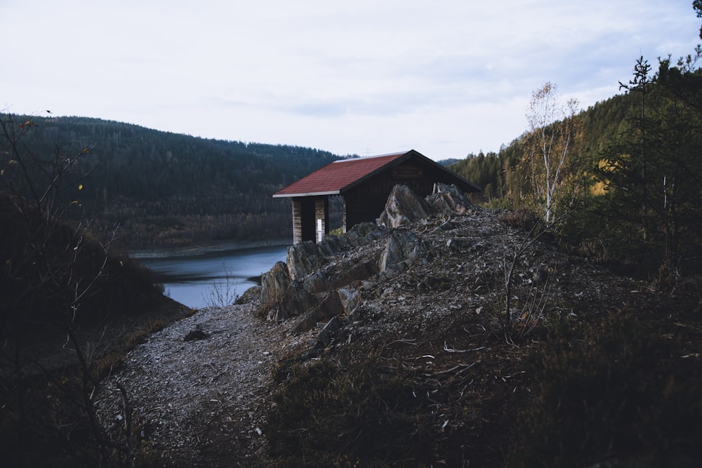 brown wooden house near lake under white clouds during daytime