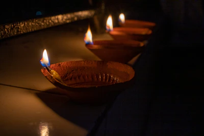 A row of brass diyas arranged on a temple altar, flickering softly in a serene setting.