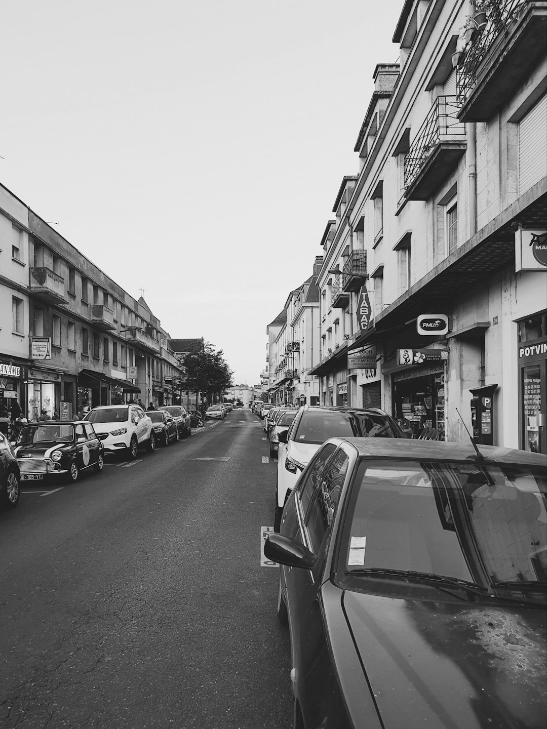 grayscale photo of cars parked on side of the road