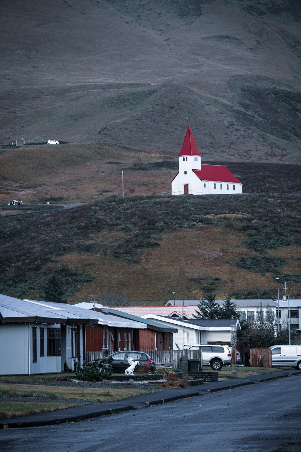 white and red concrete house near green and brown mountain during daytime