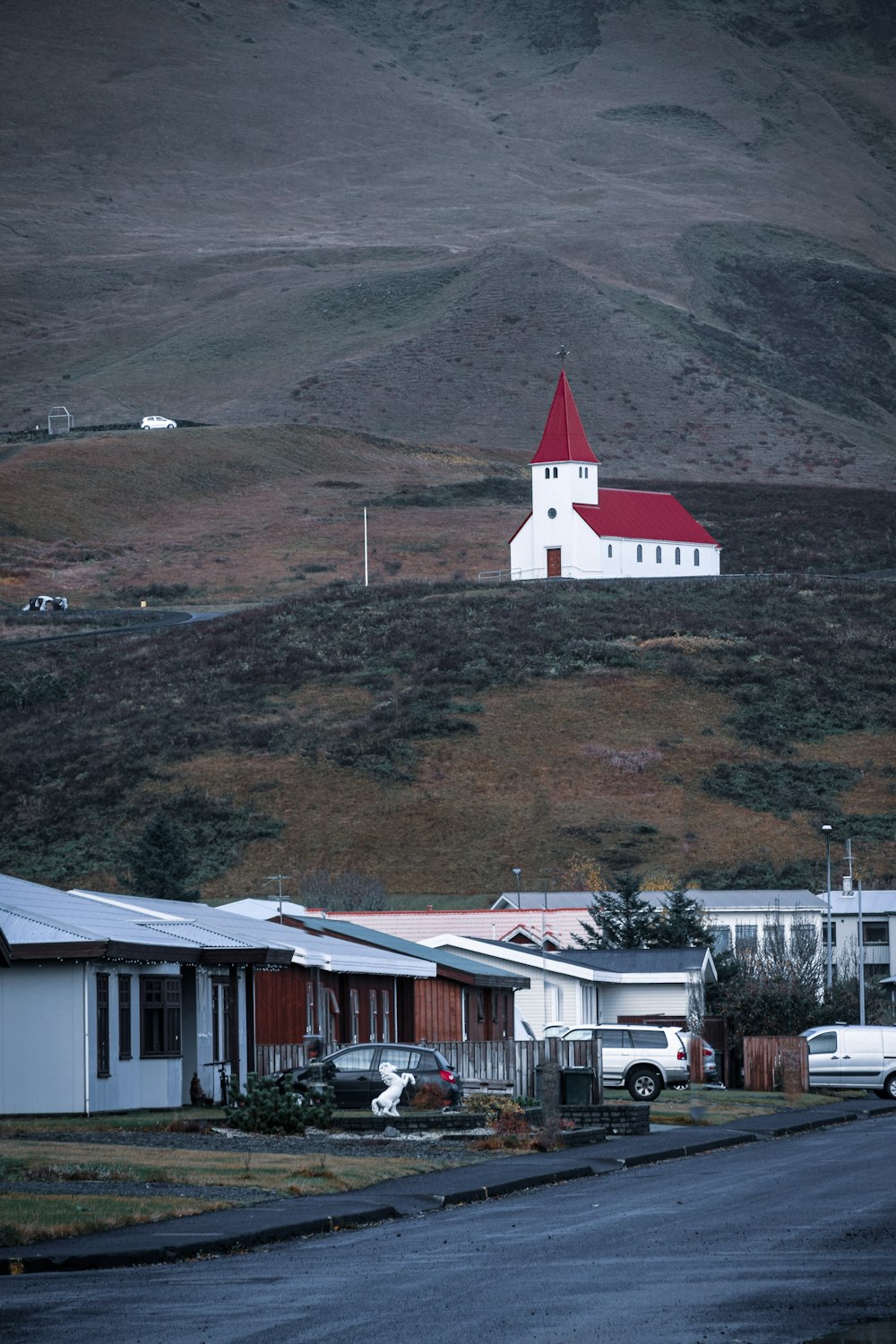Casa de concreto branca e vermelha perto da montanha verde e marrom durante o dia