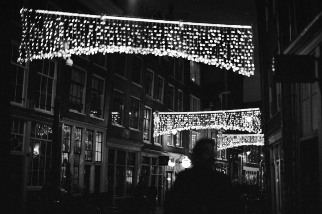 grayscale photo of man and woman standing near building