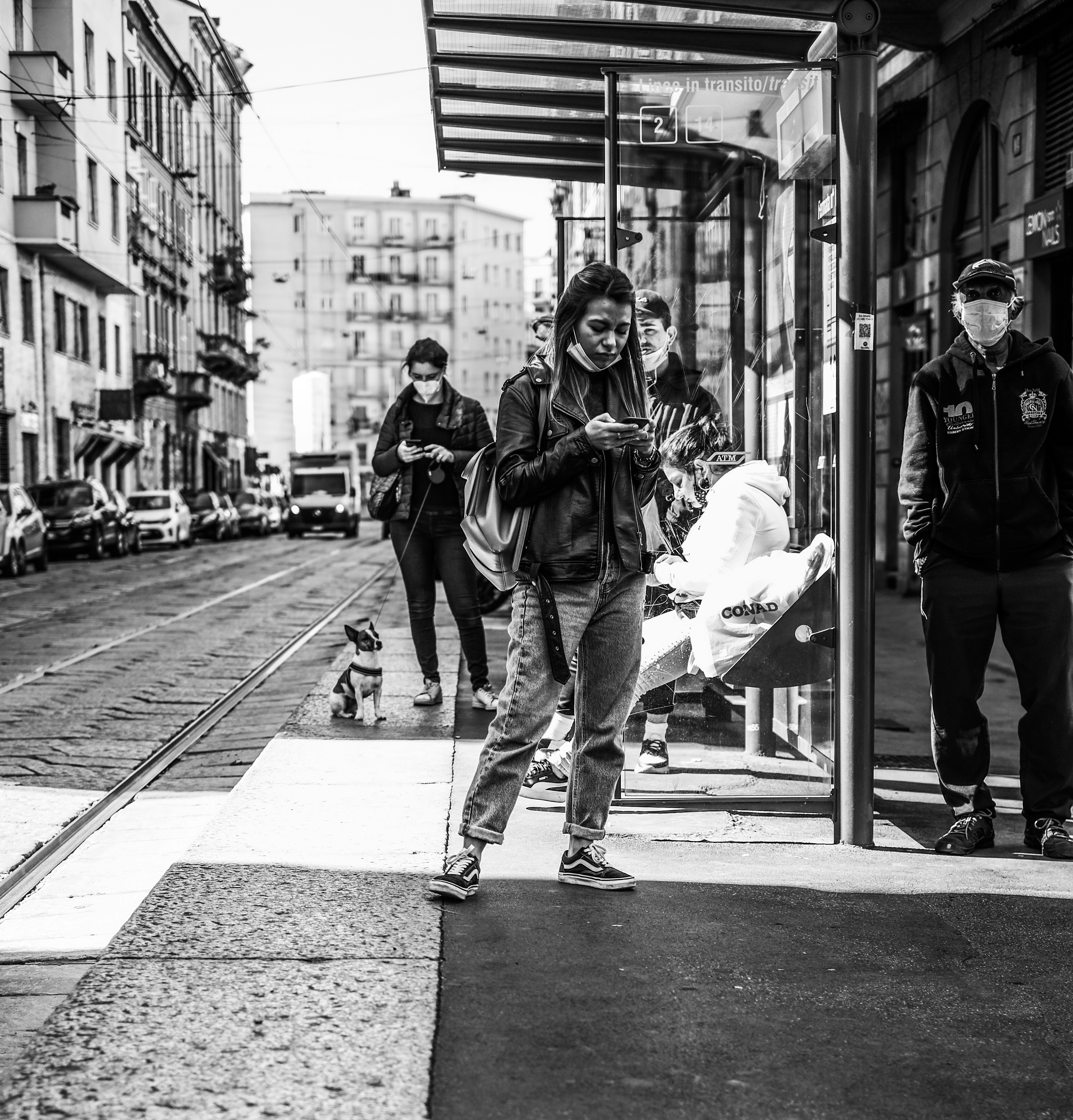 Grayscale photo of woman in black jacket and pants walking on sidewalk ...