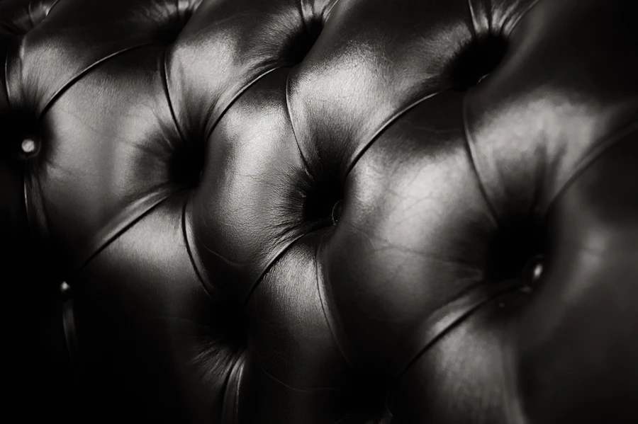 A close-up of tufted black leather upholstery, evoking quiet, tailored luxury