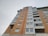 A tall, multi-story residential building with a combination of yellow and red brickwork along with glass balconies. The building features large, rectangular windows and has a modern architectural design.