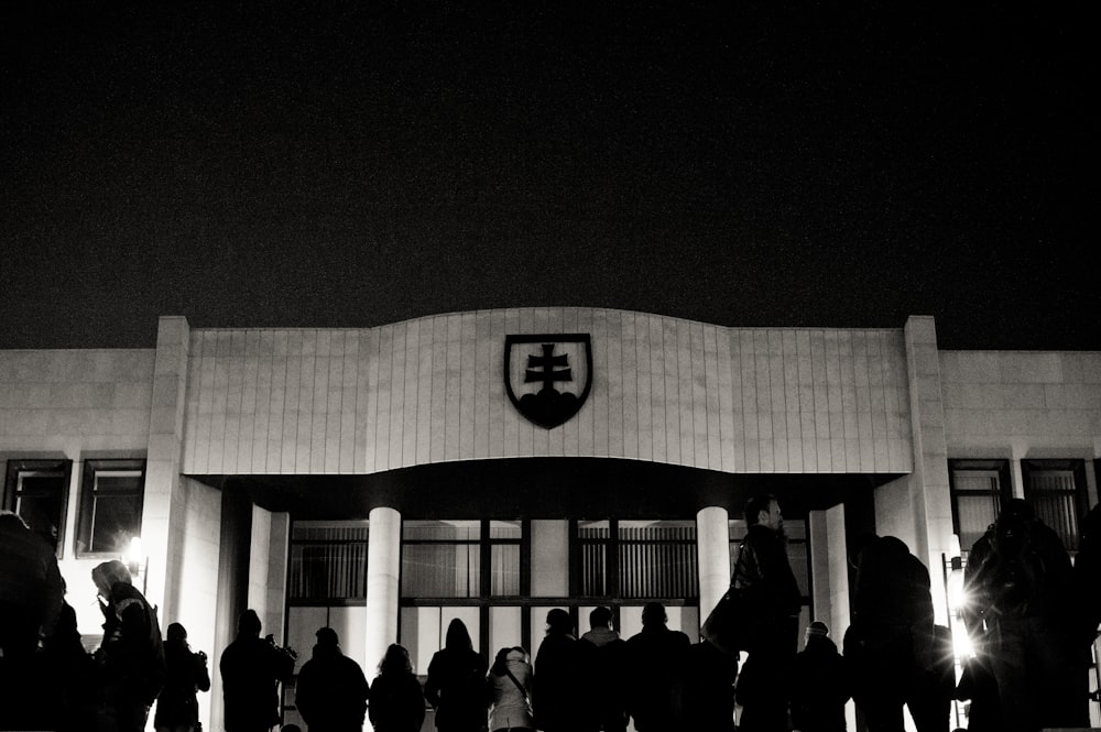 people standing in front of white building during nighttime
