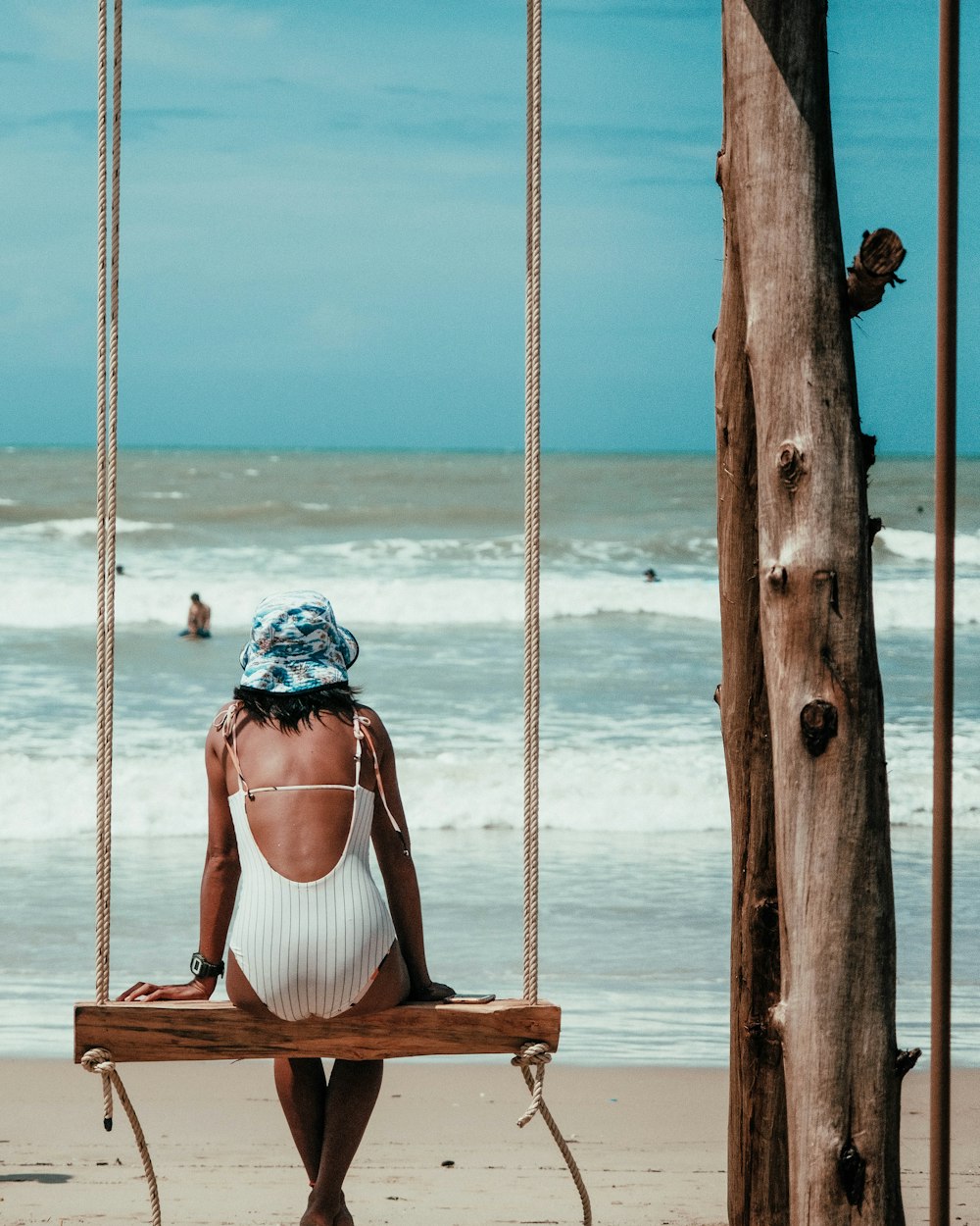 woman in red tank top sitting on brown wooden swing during daytime