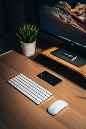 black iphone 5 beside white apple keyboard on brown wooden desk