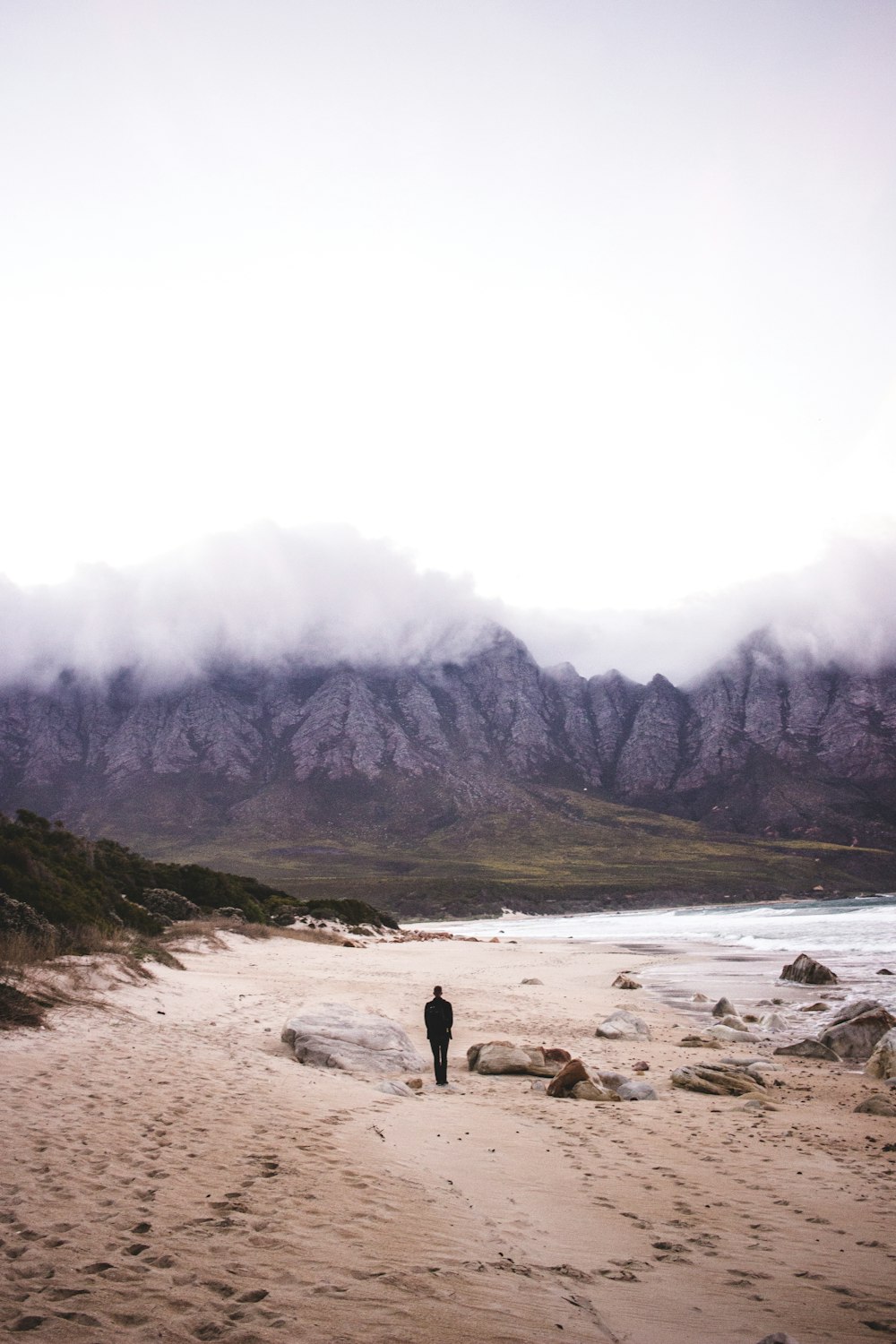 person standing on seashore near mountain during daytime