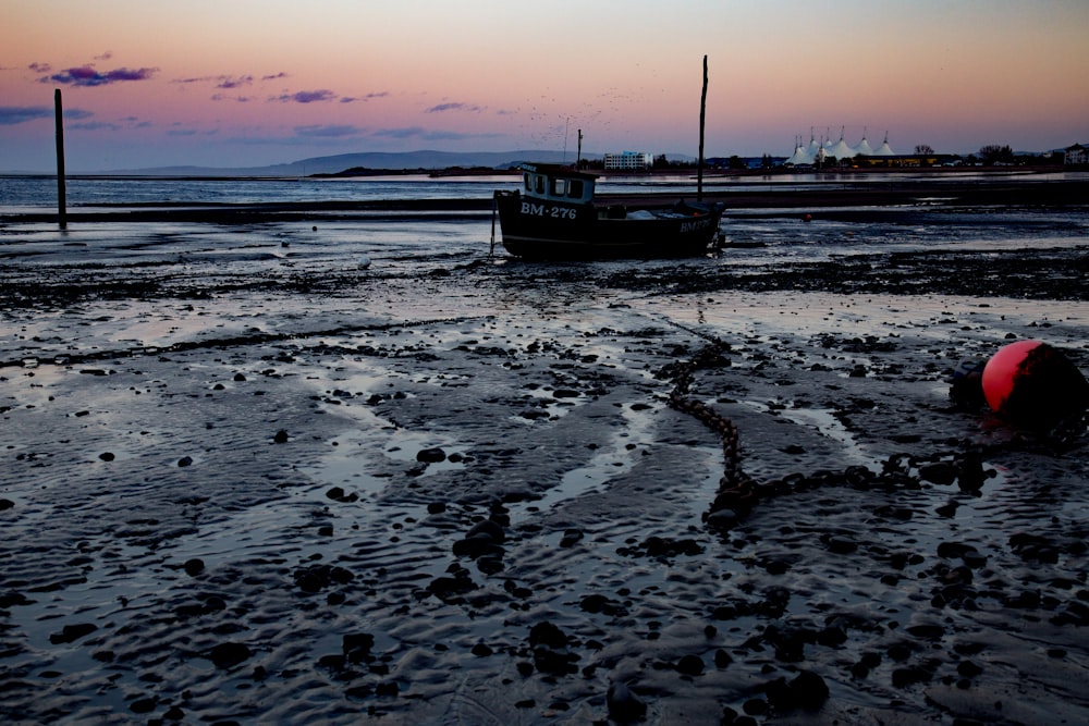 white and black boat on sea shore during sunset