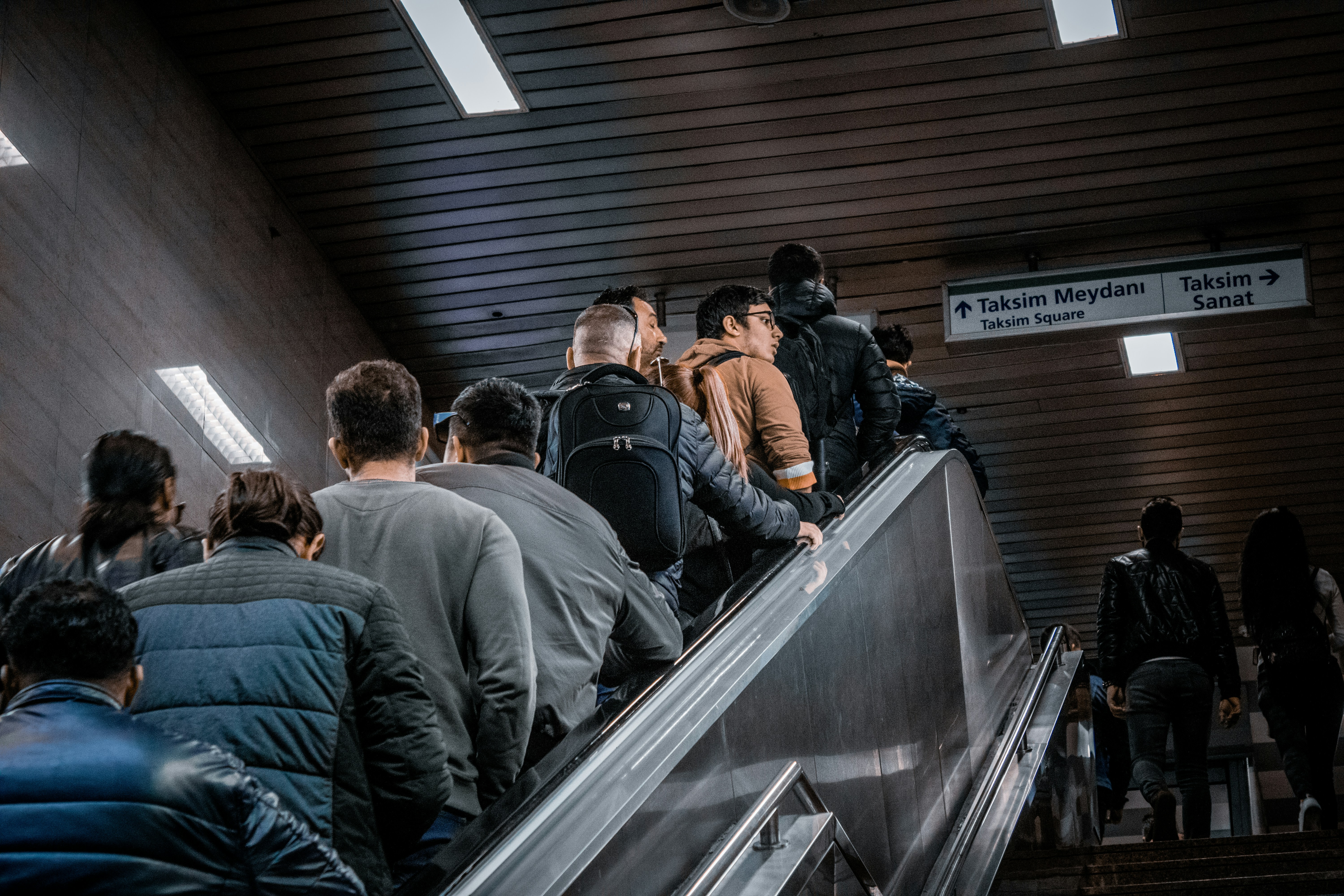 man in black jacket standing on escalator