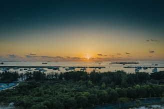 A breathtaking sunset over a serene tropical beach with a luxury yacht anchored nearby.