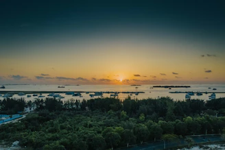 A serene sunset over a private yacht cruising turquoise waters near a secluded island.