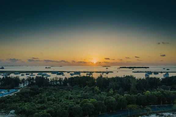 A vibrant sunset over Silver Arrow Island with a yacht anchored near the coral reefs.