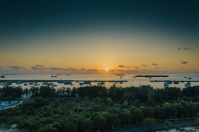 A serene sunset over a private yacht cruising turquoise waters near a secluded island.