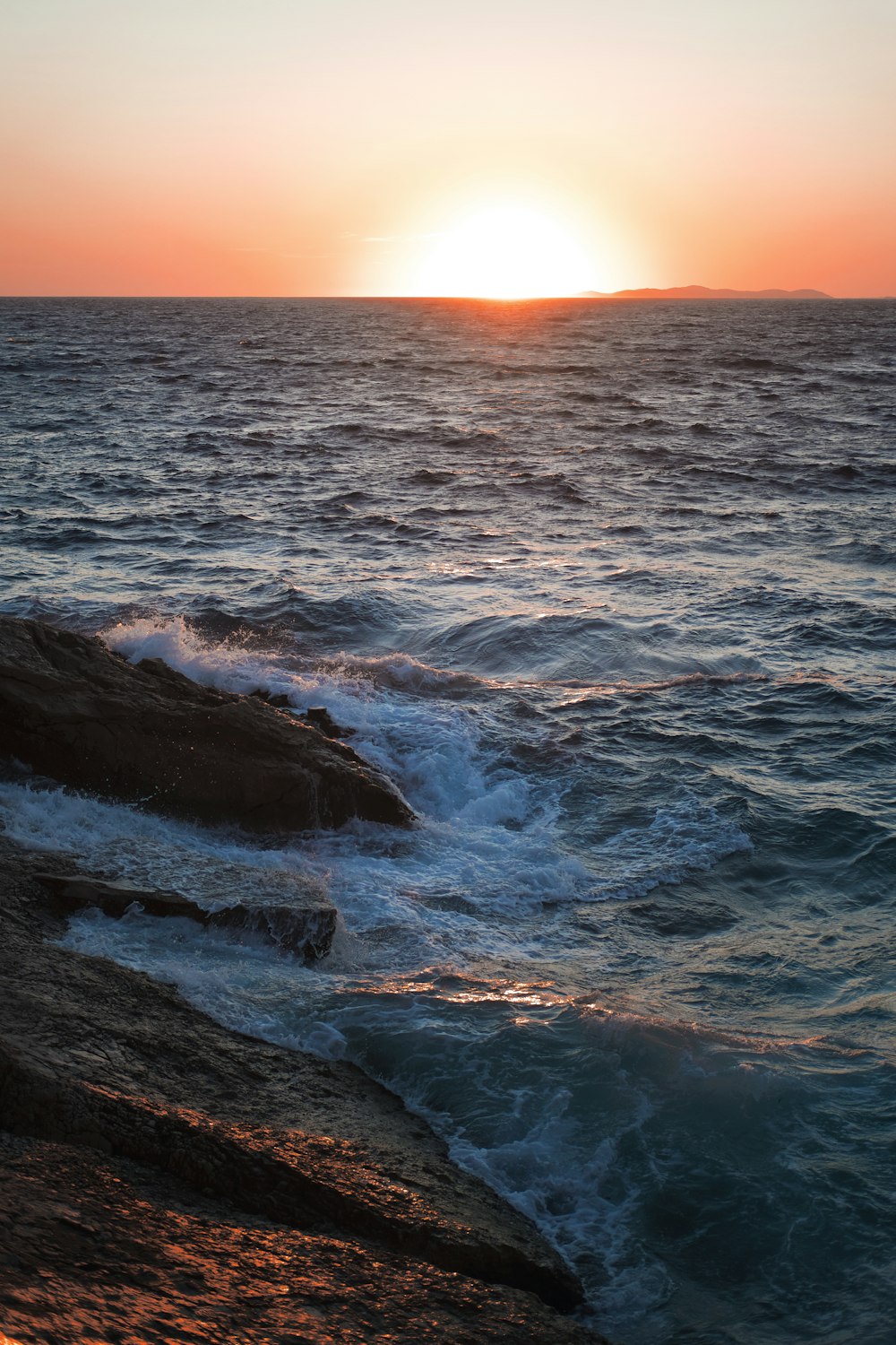 ocean waves crashing on rocks during sunset