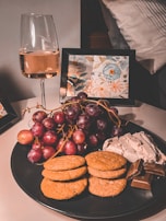 A visually engaging flat lay of wine and snacks with deep plum and black accents.