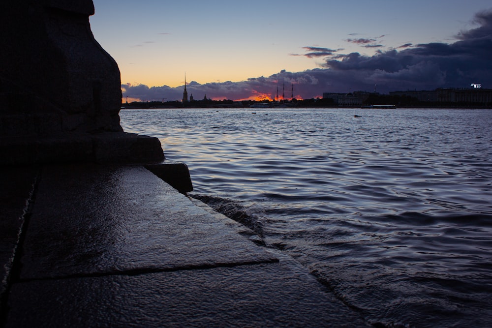 silhouette of statue near body of water during sunset