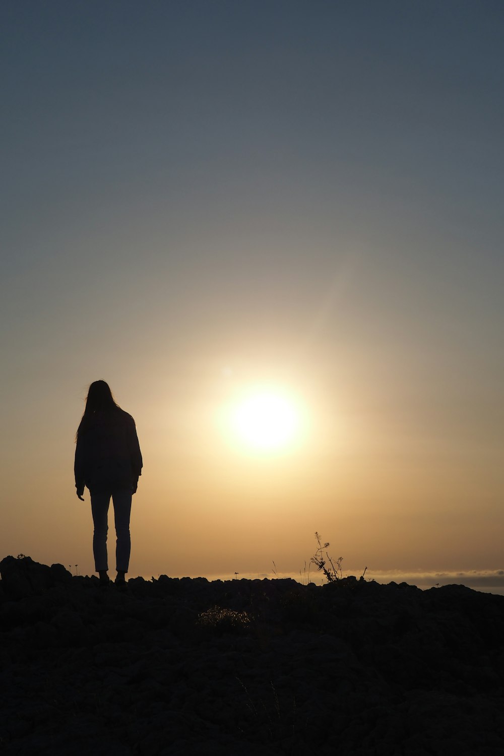 silhouette of woman standing on hill during sunset