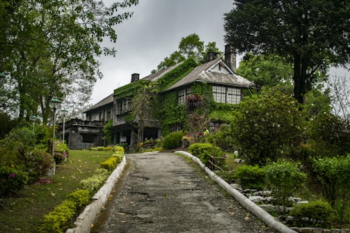 brown and white house near green trees under white clouds during daytime