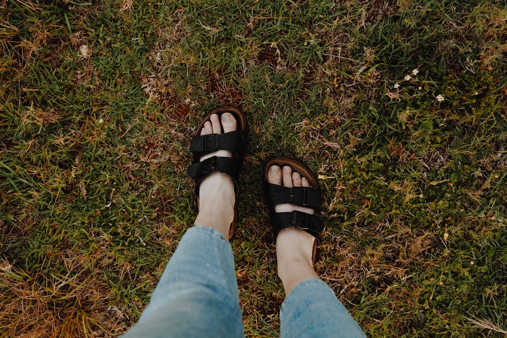 persona in pantaloncini di jeans blu che indossa sandali di pelle nera