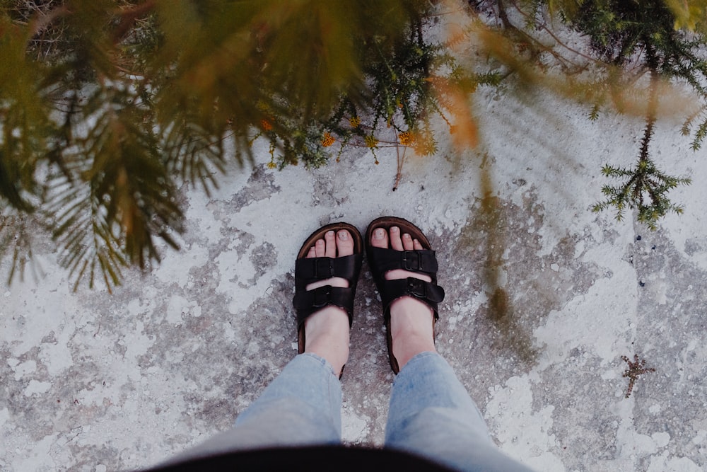 person in black leather sandals standing on snow covered ground