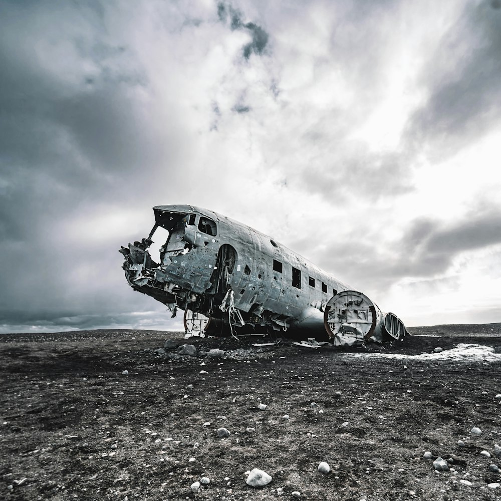 Avion blanc et noir sur sable brun sous des nuages blancs pendant la journée