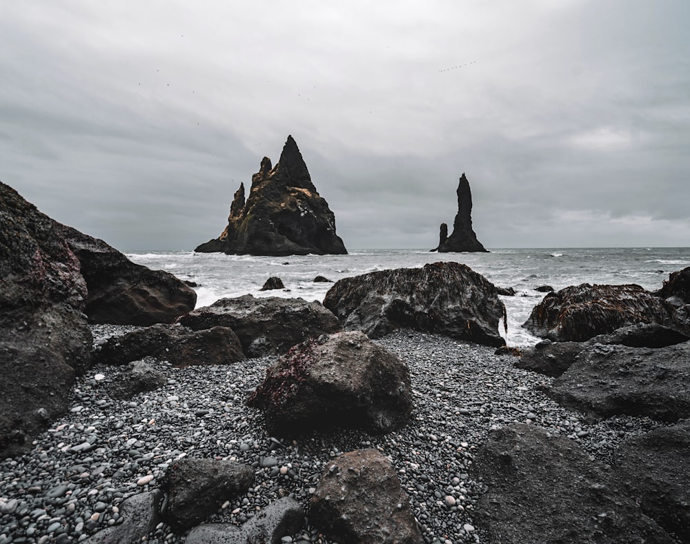 black rock formation on sea under white clouds during daytime