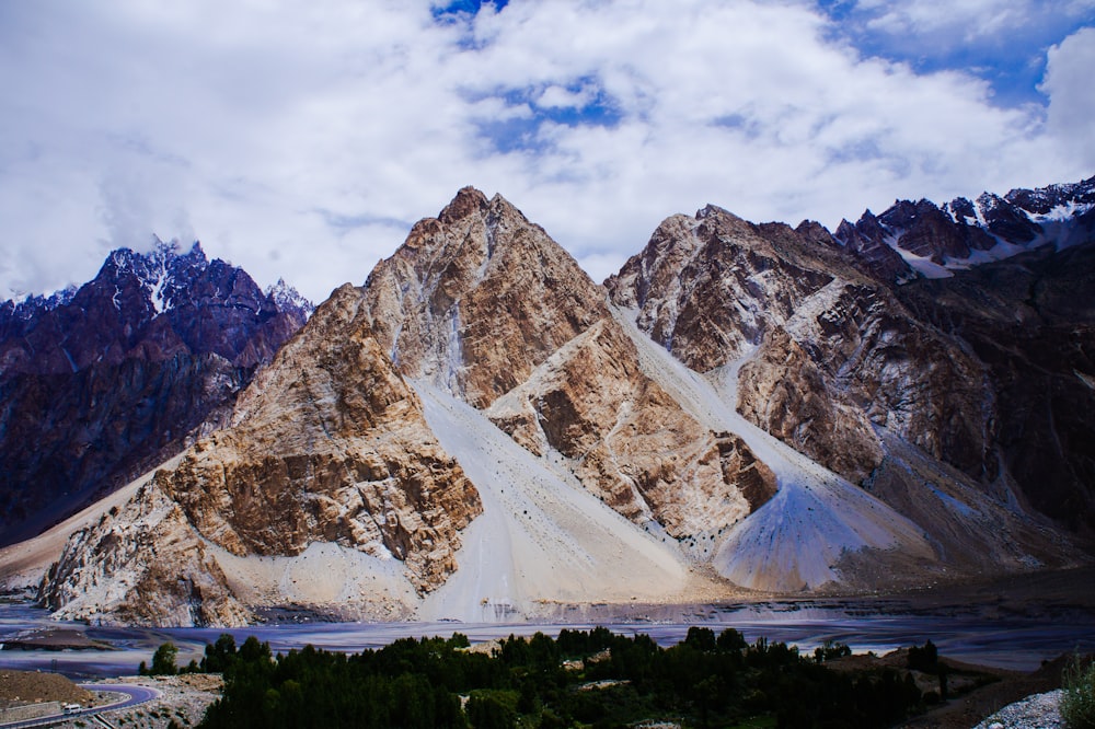 Montaña marrón y blanca bajo nubes blancas durante el día