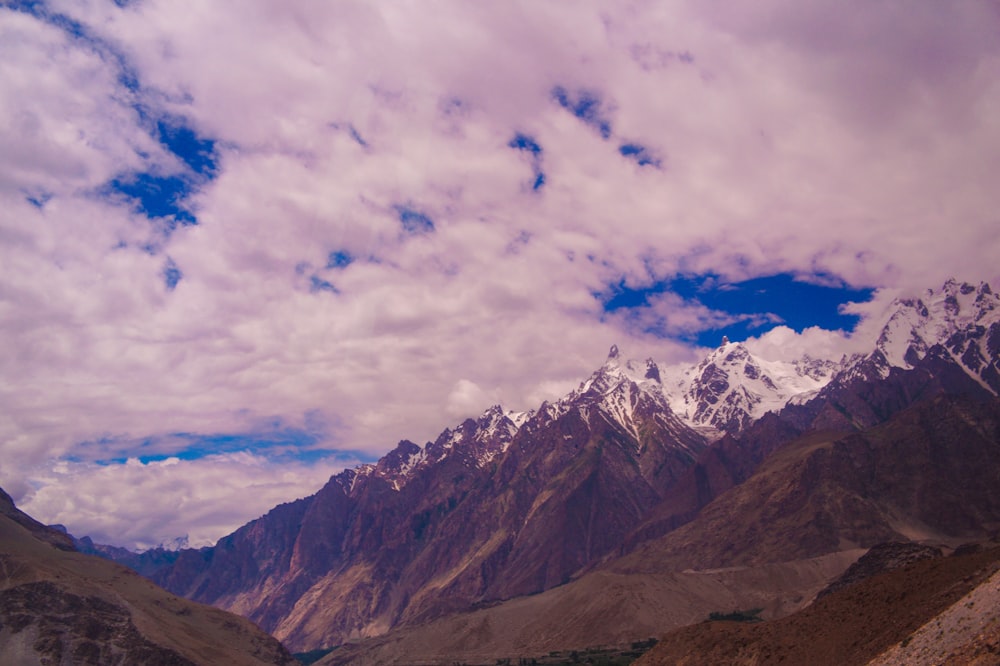 brown and white mountains under white clouds and blue sky during daytime