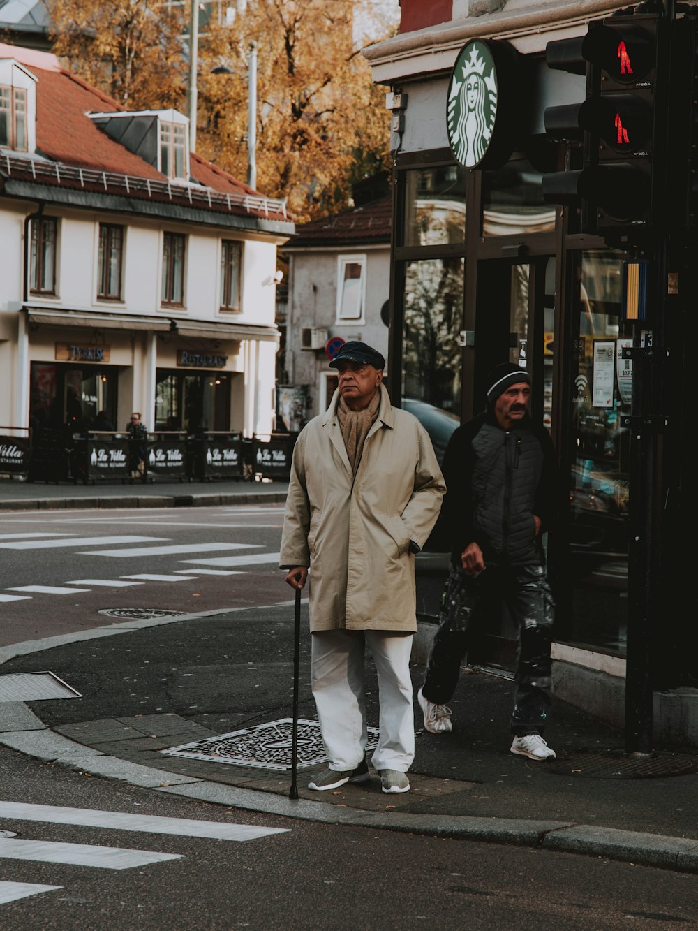 man in brown coat walking on pedestrian lane during daytime