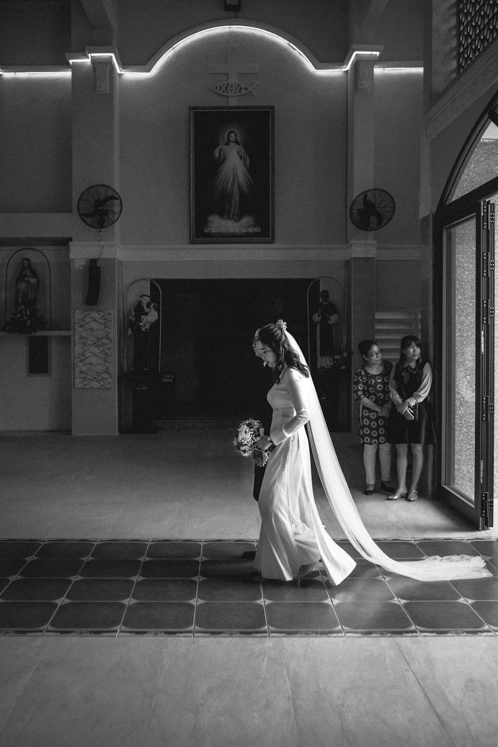 foto in scala di grigi della sposa e dello sposo in piedi vicino alla porta