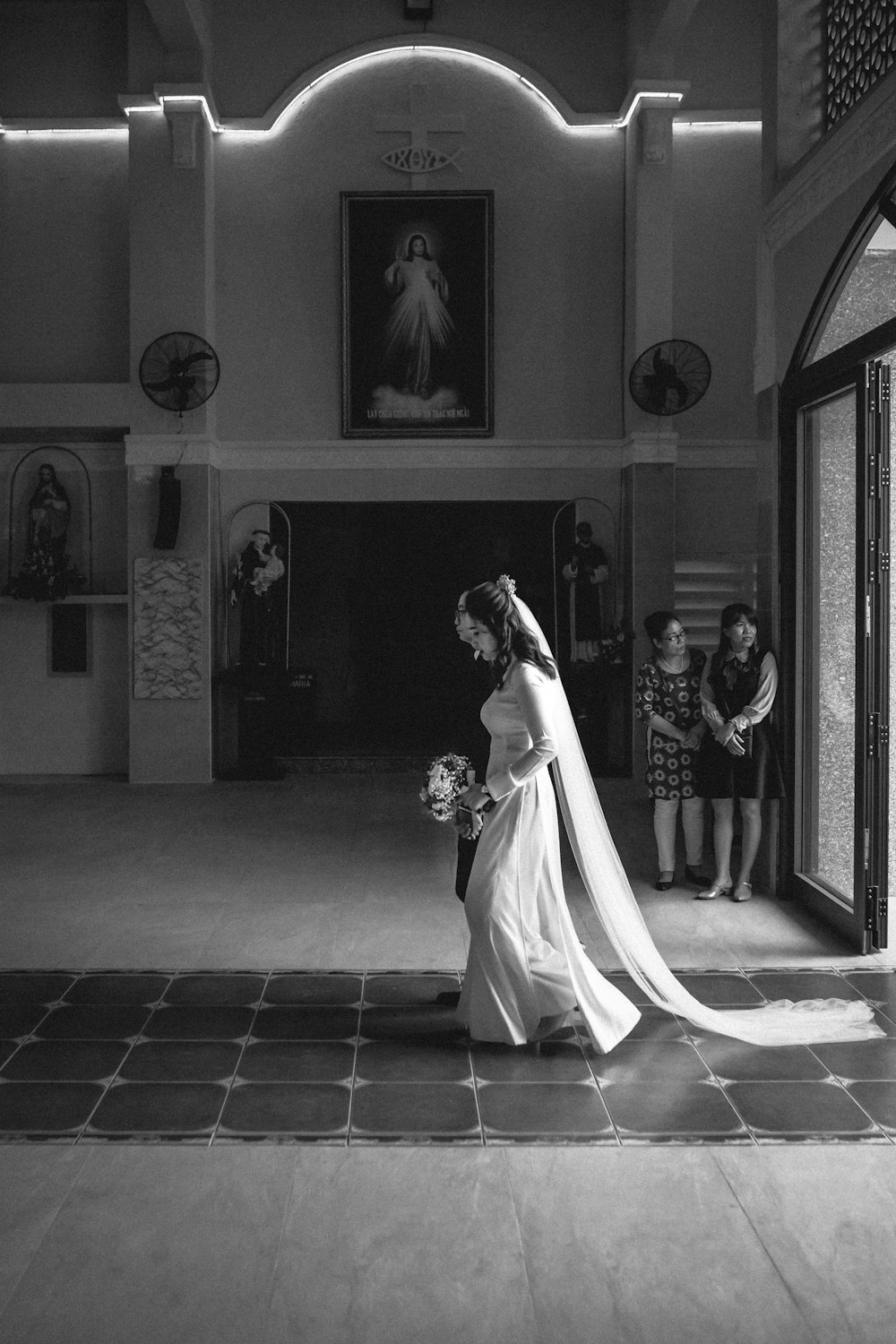 grayscale photo of bride and groom standing near door