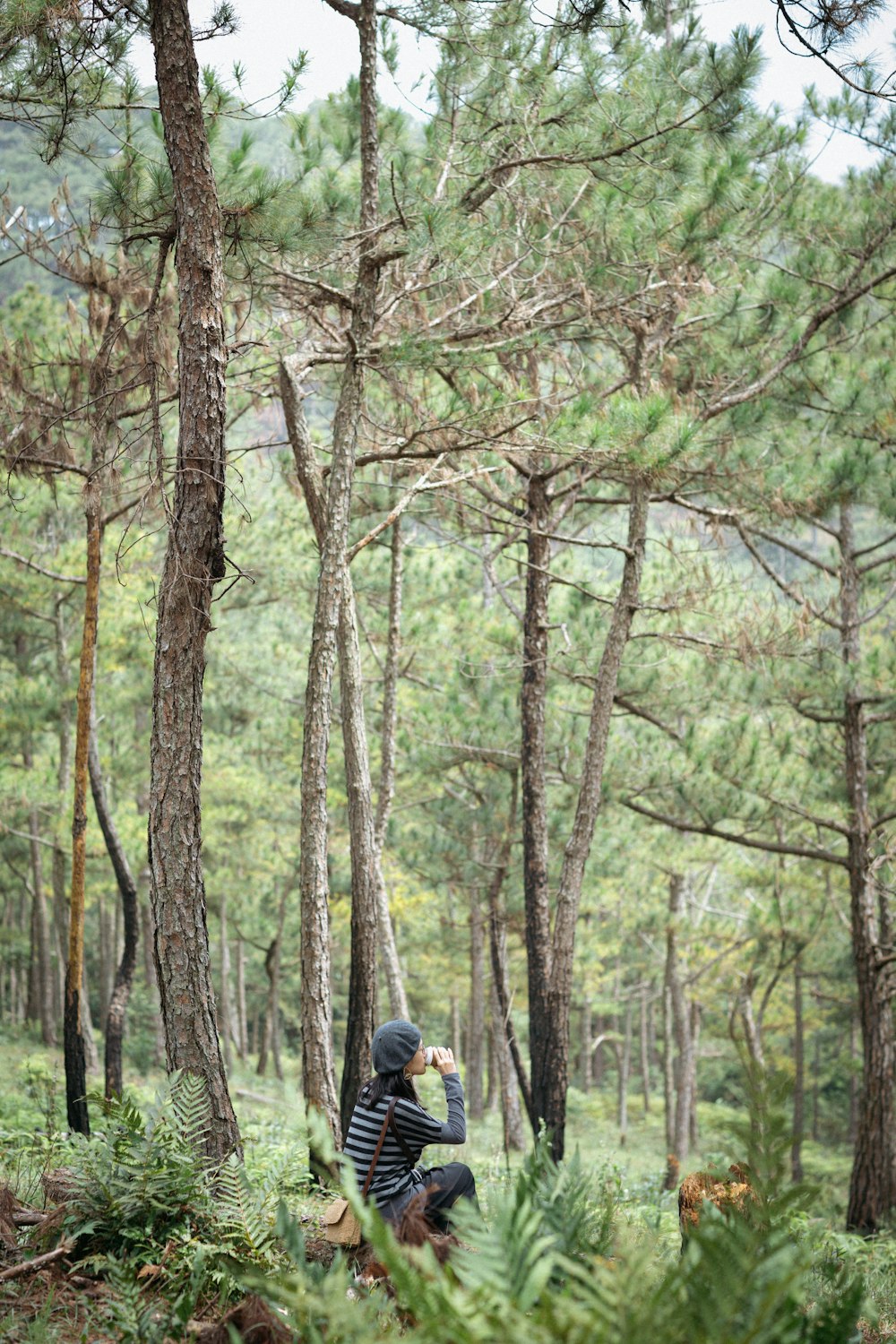 검은 재킷과 파란색 데님 청바지를 입은 사람이 낮에 숲을 걷고 있다