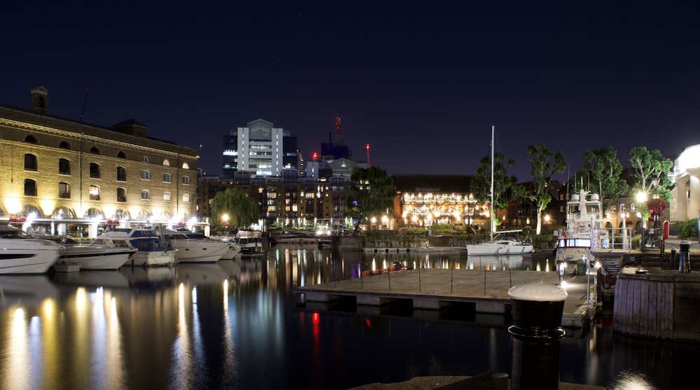 white boat on water near city buildings during night time