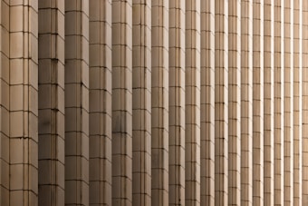 Rows of vertically aligned rectangular panels create a repetitive, symmetrical pattern. The panels are made of a beige or light brown material and seem to form part of a large architectural facade.