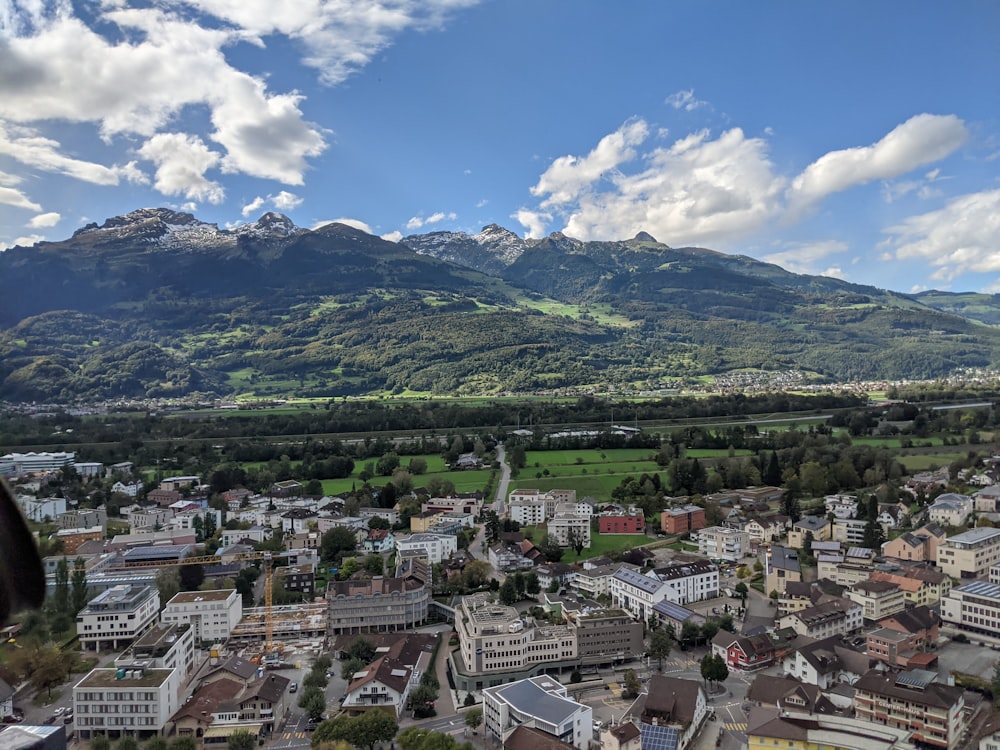 aerial view of city buildings and green mountains during daytime