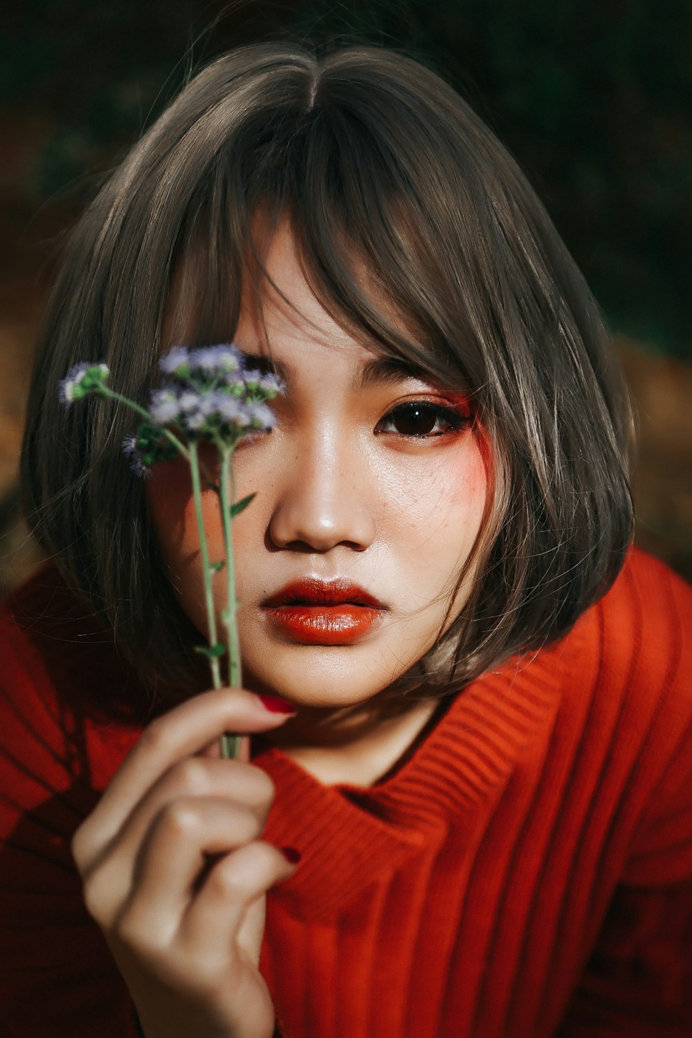 woman in red sweater holding white flower