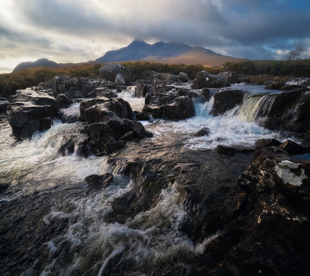 rocky river under cloudy sky during daytime